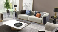 Modern living room with beige sofa, colorful pillows, marble coffee table, black lamps, and art