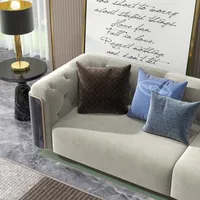 Modern grey sofa with blue pillows by a black side table and framed wall quote