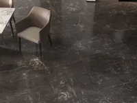 Close up of dark marble floor with beige chair and edge of white marble table