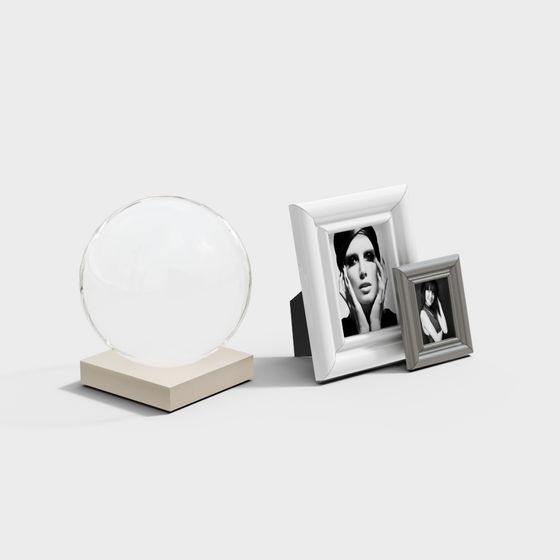 Clear glass sphere on beige base with two silver picture frames on white background