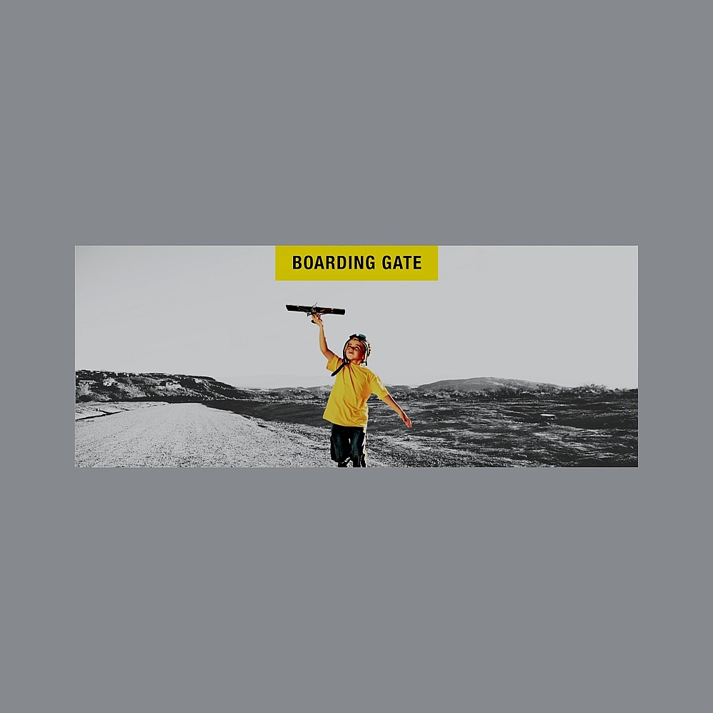 Child in yellow shirt holding toy plane on grey background
