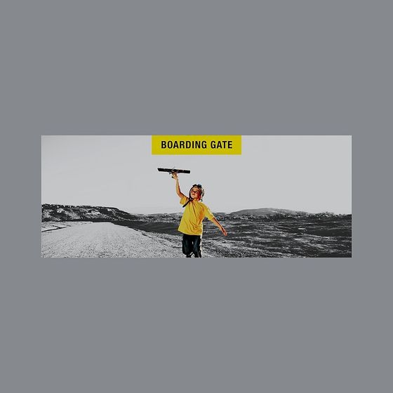 Child in yellow shirt holding toy plane on grey background