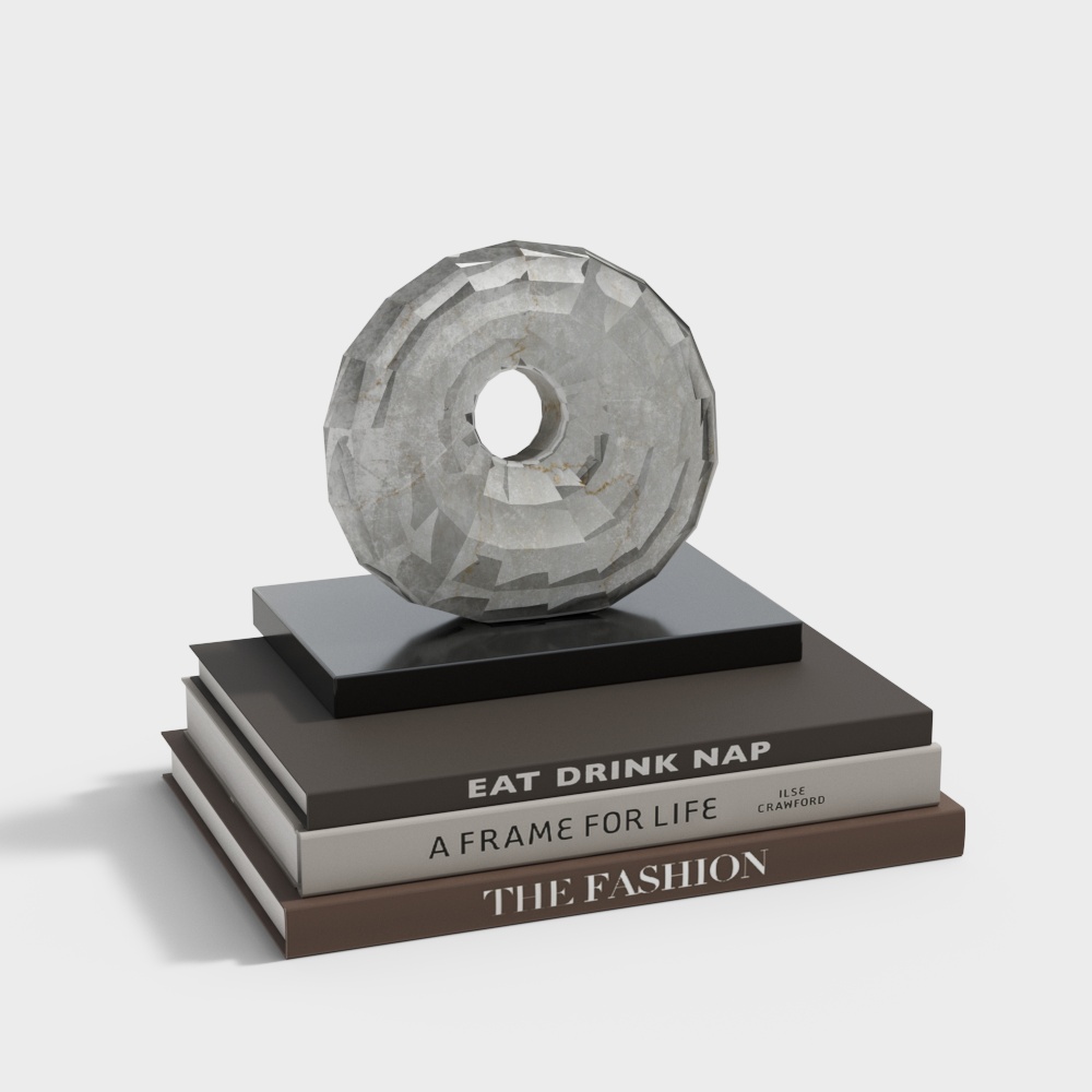 Grey stone donut sculpture on black base with three books on white background