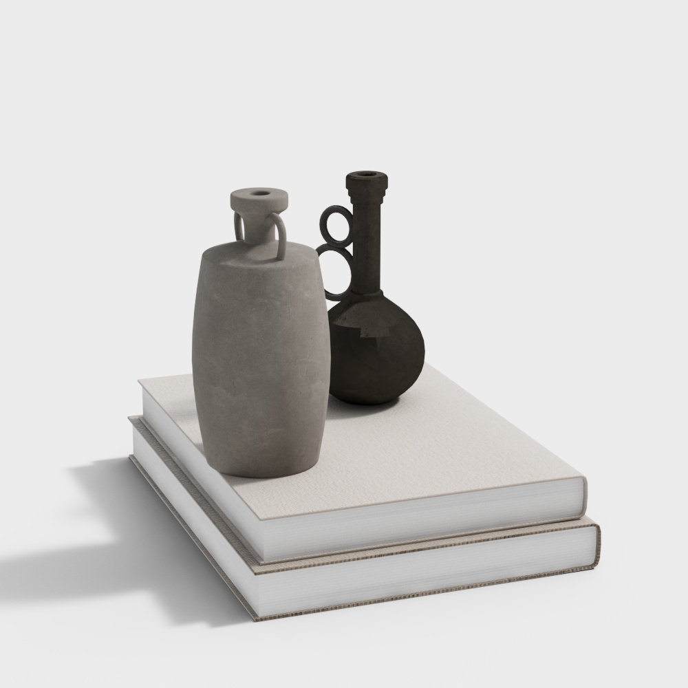 Two modern decorative vases in grey and black placed on stacked white books on white background
